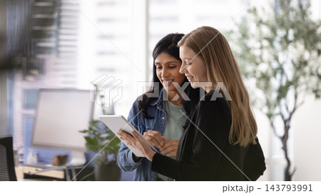 Multiethnic women business professionals checking tablet at modern office workspace 143793991