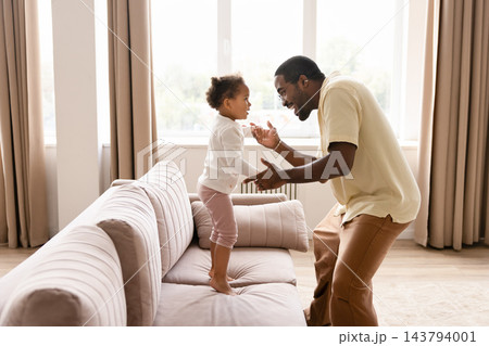 Black father playing with toddler daughter at home 143794001