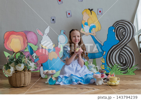 Centered Caucasian Girl Between Large Wonderland Cutouts And Tea Set, Eight Marker Visible, Soft Window Illumination, Pastel Props, Serene Celebrant Posture, DIY Party Backdrop And Cozy Interior 143794239