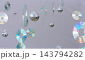 Compact discs and disco balls dangle at various heights in studio setting. Iridescent rainbow reflections shine across smooth shiny surfaces creating festive party atmosphere. 143794282