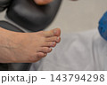 Bare human foot rests comfortably during podiatry examination in clinical medical office. Professional healthcare setting provides calm environment for routine foot care checkup. 143794298