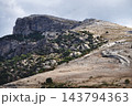 Rugged rocky mountain landscape with cliffs and sparse vegetation under cloudy sky 143794363