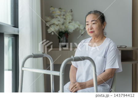 Senior woman sitting with walker at home reflecting on her life. Senior woman sitting with walker at home reflecting on her life. 143794412