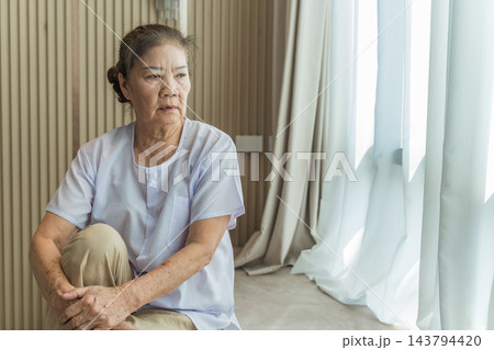 Senior woman reflecting while sitting in bright room for wellness. 143794420