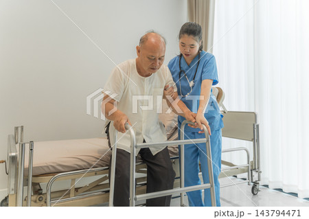 Nurse assisting senior man with walker in hospital room for rehabilitation. Nurse assisting senior man with walker in hospital room for rehabilitation. 143794471