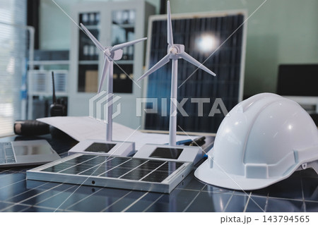 Two Asian engineers wearing hardhats and safety vests discussing solar panel installation and renewable energy project in the office. Two Asian engineers wearing hardhats and safety vests discussing solar panel installation and renewable energy project in the office. 143794565
