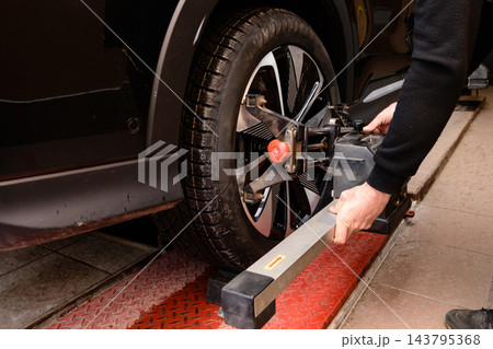 Wheel alignment and alignment on the car service platform. Car tire alignment process takes place in a vehicle service center during the afternoon Wheel alignment and alignment on the car service platform. Car tire alignment process takes place in a vehicle service center during the afternoon 143795368