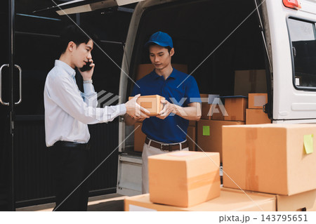 Young businessman signing a delivery receipt document on a clipboard held by a courier in a blue uniform. 143795651