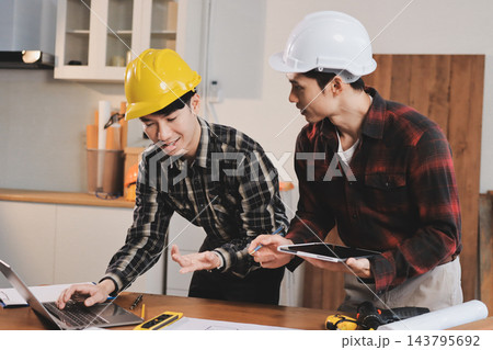 Asian architect and engineer team checking architectural house model using measuring tape on the table at office studio. Asian architect and engineer team checking architectural house model using measuring tape on the table at office studio. 143795692