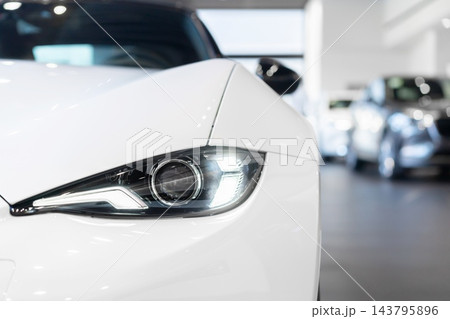 front view of new modern white sports car led headlight in showroom front view of new modern white sports car led headlight in showroom 143795896