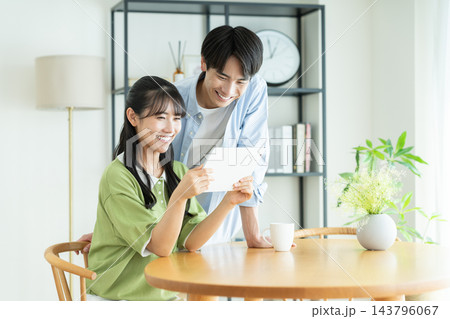 家でタブレットを見る若いカップル 家でタブレットを見る若いカップル 143796067