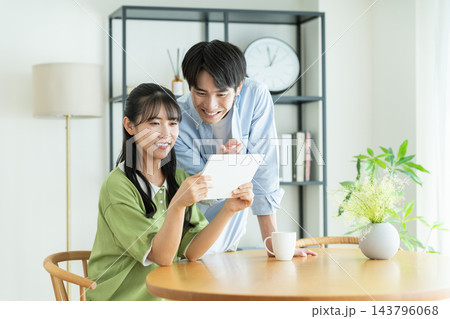 家でタブレットを見る若いカップル 家でタブレットを見る若いカップル 143796068