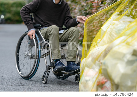 ゴミを捨てる車椅子のシニア男性 ゴミを捨てる車椅子のシニア男性 143796424