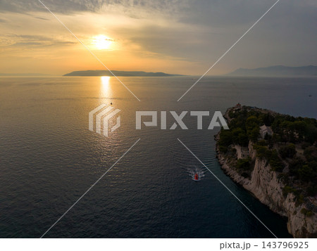 Makarska Croatia coastline meets Adriatic at sunset, as bright reflection crosses rippled water. Wooded rocky peninsula and distant island silhouettes complete tranquil coastal vista. Makarska Croatia coastline meets Adriatic at sunset, as bright reflection crosses rippled water. Wooded rocky peninsula and distant island silhouettes complete tranquil coastal vista. 143796925