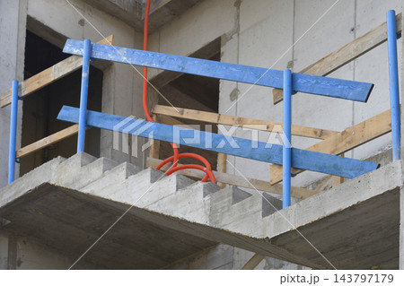An unfinished concrete staircase with blue safety railings on a construction site 143797179