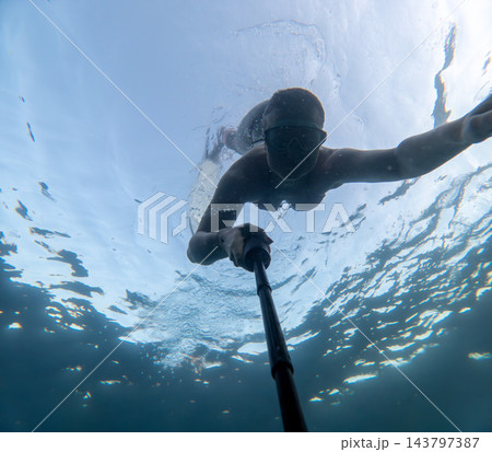 Clear sea exploration captured by young woman taking underwater selfie with monopod Clear sea exploration captured by young woman taking underwater selfie with monopod 143797387