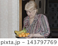 An elderly woman a grandmother brings fruit on a plate to her young grandson in the room and feeds him. Caring for children and the elderly parental love. 143797769