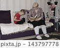 grandmother is reading colorful book grandson, has leaned in closer to listen. grandmother wearing glasses, boy, dressed red T-shirt, is intently examining the book and listening to the story. 143797778