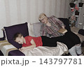 grandmother is reading colorful book grandson, has leaned in closer to listen. grandmother wearing glasses, boy, dressed red T-shirt, is intently examining the book and listening to the story. 143797781