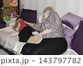 grandmother is reading colorful book grandson, has leaned in closer to listen. grandmother wearing glasses, boy, dressed red T-shirt, is intently examining the book and listening to the story. 143797782