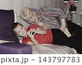 grandmother is reading colorful book grandson, has leaned in closer to listen. grandmother wearing glasses, boy, dressed red T-shirt, is intently examining the book and listening to the story. 143797783