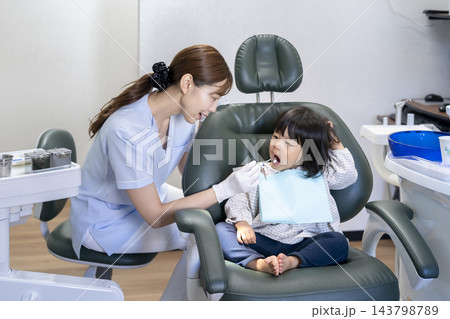 2歳の女の子にフッ素の塗布をする歯科衛生士 2歳の女の子にフッ素の塗布をする歯科衛生士 143798789