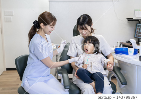 歯科衛生士にフッ素塗布を受ける2歳の女の子 歯科衛生士にフッ素塗布を受ける2歳の女の子 143798867