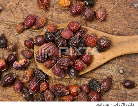 Dried rosehip fruits in a wooden spoon and on a table close-up. 143799232