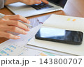 スマホと手帳を確認する手元 143800707