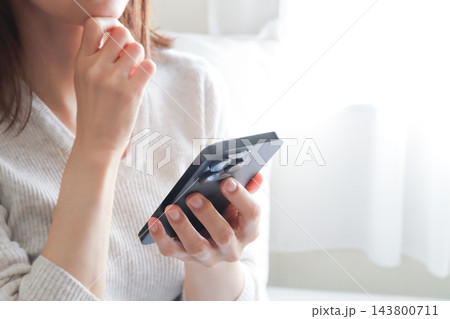 スマホを見て悩む女性 143800711