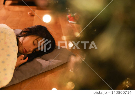 クリスマスツリーのそばで毛布をかけて眠る子ども クリスマスツリーのそばで毛布をかけて眠る子ども 143800714