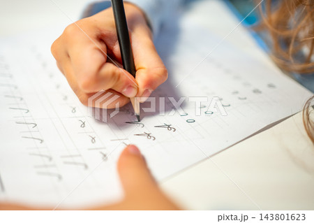 First grade student practices writing letters with pencil in workbook. Early literacy and handwriting skills develop with selective focus and shallow depth of field First grade student practices writing letters with pencil in workbook. Early literacy and handwriting skills develop with selective focus and shallow depth of field 143801623