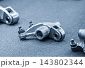 Close-up of automotive roller rocker arm parts in a modern blue tone scene 143802344
