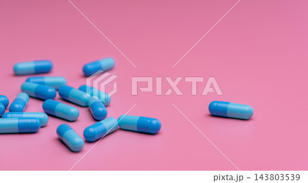 Blue capsule pills scattered on pink background with large copy space, prescription medicine and pharmaceutical treatment concept for healthcare, pharmacy, drug research and patient care. Blue capsule pills scattered on pink background with large copy space, prescription medicine and pharmaceutical treatment concept for healthcare, pharmacy, drug research and patient care. 143803539