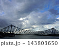 Majestic steel cantilever Howrah Bridge over Hooghly river under dramatic cloudy sky in Kolkata 143803650