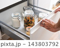 Person opening organized kitchen pantry drawer with glass food jars 143803792