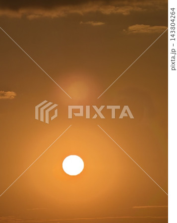 オレンジ色に染まる空に輝く丸い太陽 オレンジ色に染まる空に輝く丸い太陽 143804264