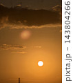 厚い雲と丸い太陽が浮かぶオレンジ色の空 143804266