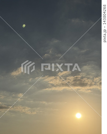 広い空にたなびく雲と右下に輝く太陽 143804268