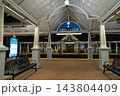 An empty Winter Park train station platform is brightly lit at night with benches and white columns. The scene shows covered railway architecture, brick pavement, signs, and tracks across the platform 143804409