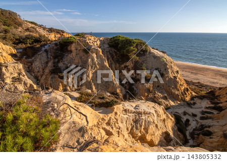 Scenic sunset view of sandstone cliffs and canyon leading to Arenosillo beach in Mazagon, Huelva, Spain. Great for travel guides, Andalusian tourism, and nature blogs. Scenic sunset view of sandstone cliffs and canyon leading to Arenosillo beach in Mazagon, Huelva, Spain. Great for travel guides, Andalusian tourism, and nature blogs. 143805332