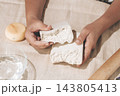 A woman's hands, are holding two halves, of a block of polymer clay, 143805413