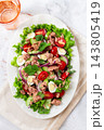 salad with canned tuna, cherry tomatoes, cucumber, and quail eggs on a white plate 143805419