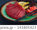 Fresh tuna sashimi served with lemon, wasabi, and pickled ginger on a dark background 143805423