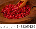 Bright red peppercorns, in a wooden bowl, with a small wooden tray, 143805429