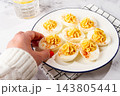 stuffed eggs with paprika, on a plate, a woman's hand reaches for it, 143805441
