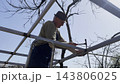 Male laborer uses a hammer to strike welded metal joints on carport frame. Adult worker refines and secures the structure, carefully adjusting welded connections metal installation work at the site 143806025