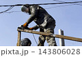Young mechanic in protective gloves polishing iron using electric grinder wheel at construction. Professional repairman grinding metal details with circular saw on house at sunny day. Slow mo 143806028
