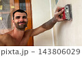 POV of young man uses brush to clean finished wall surface removing dust and small imperfections after renovation work. Male worker carefully prepare smooth wall for next finishing stage inside room 143806029