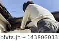 Manual laborer in protective mask welds iron detail at construction. Professional young repairman with welding machine working at the site. Male welder operating with metal on house. Close up 143806033